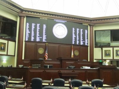 A large screen in a courtroom displays a list of names