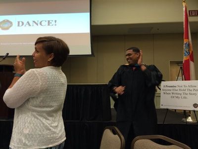 A man and a woman are standing in front of a screen that says dance.