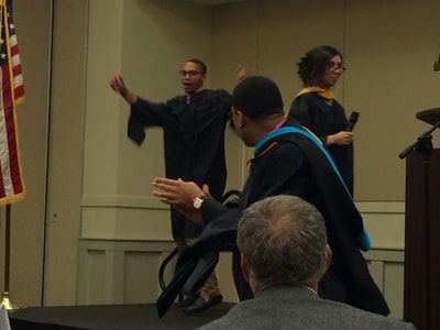 A group of people in graduation gowns are standing on a stage