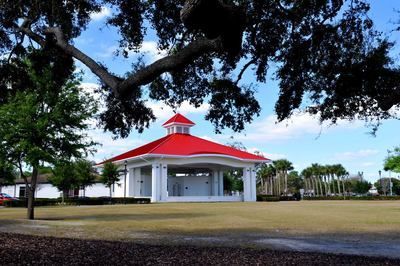 A white building with a red roof in a park