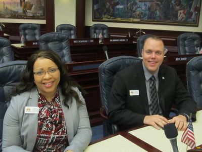 A man and a woman are sitting at a table in a conference room