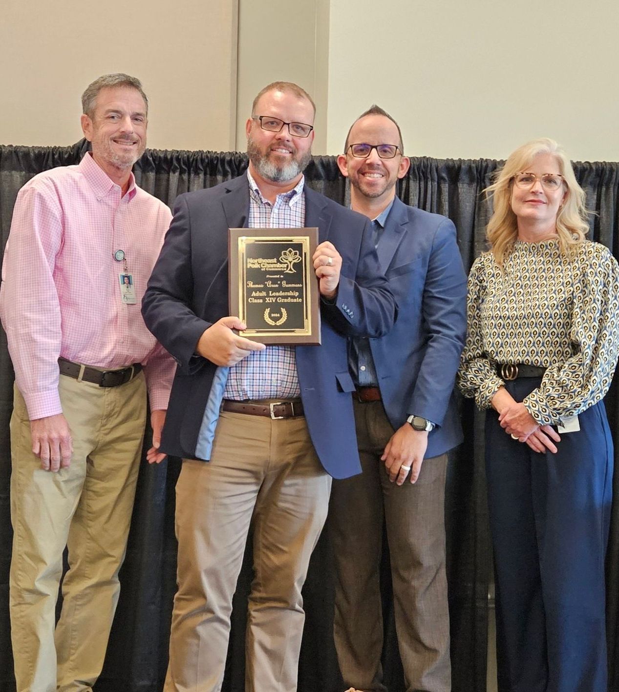 A group of people standing next to each other holding a plaque