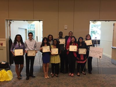 A group of people are standing in a room holding certificates.