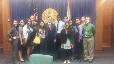 A group of people are posing for a picture in front of an american flag.