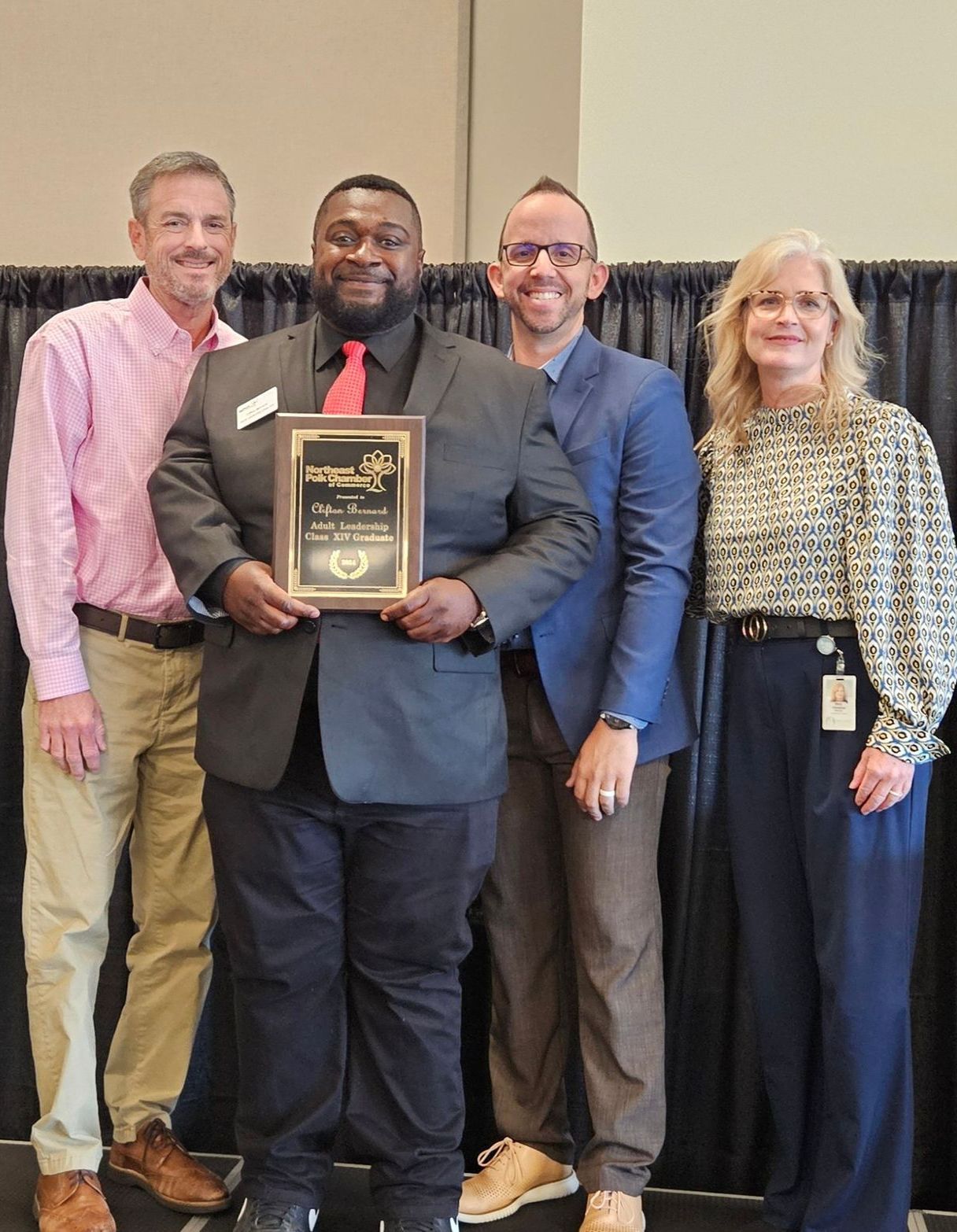 A group of people are posing for a picture while a man holds a plaque.