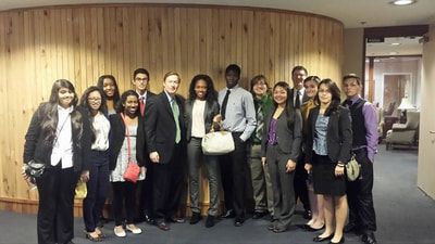 A group of people are posing for a picture in front of a wooden wall.