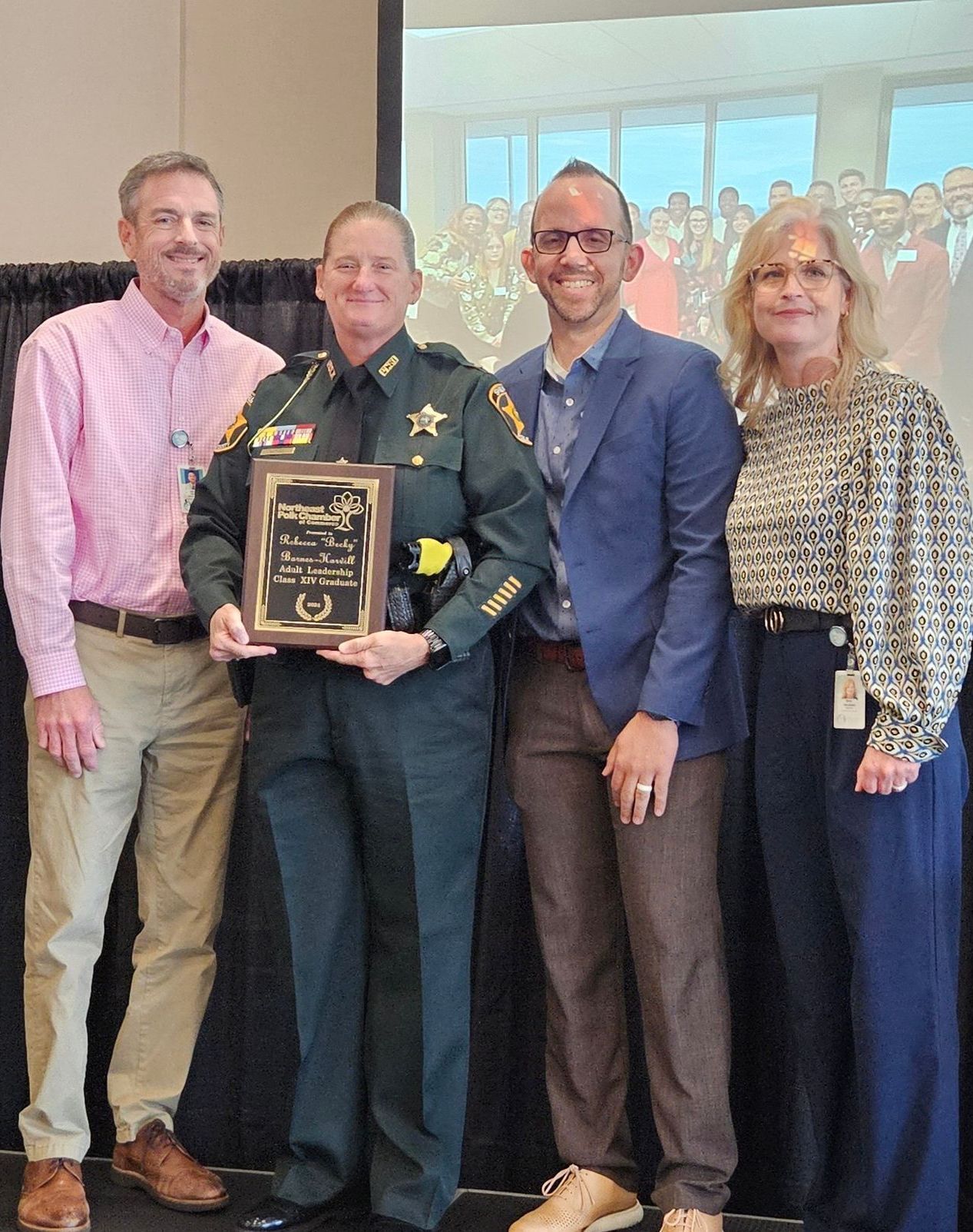 A group of people standing around a man in a military uniform holding a plaque.