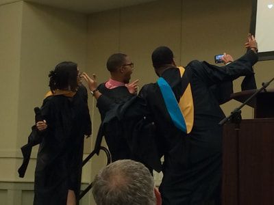 A group of people in graduation gowns are standing in front of a podium.