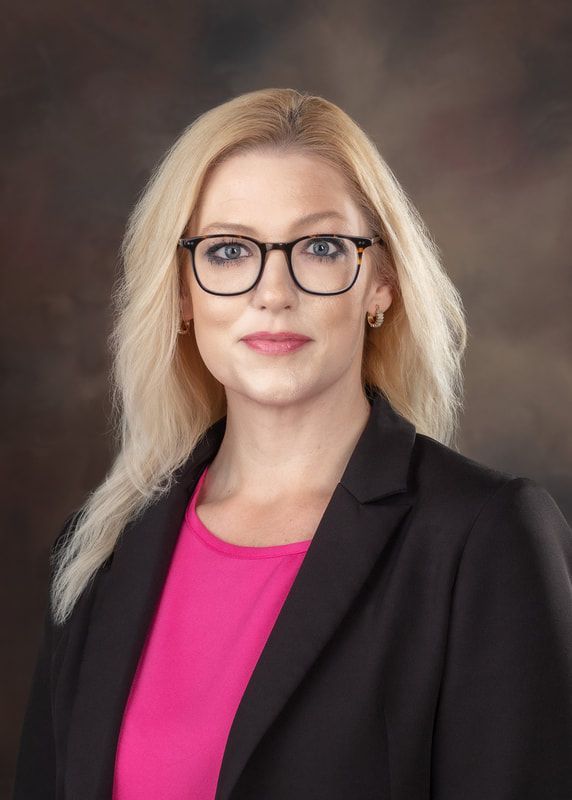 A woman wearing glasses and a black jacket is posing for a picture.