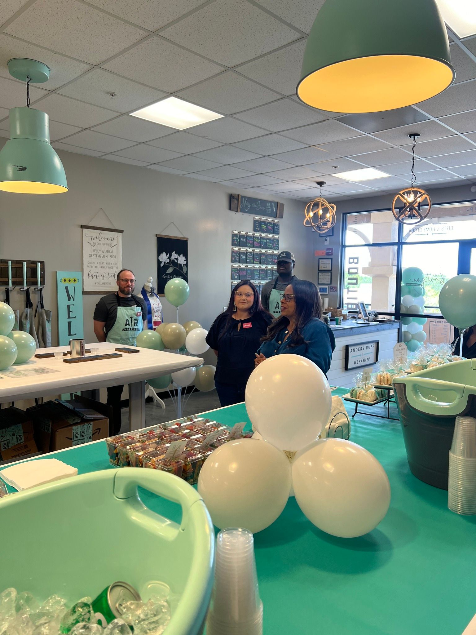 A group of people are standing around a table with balloons on it.