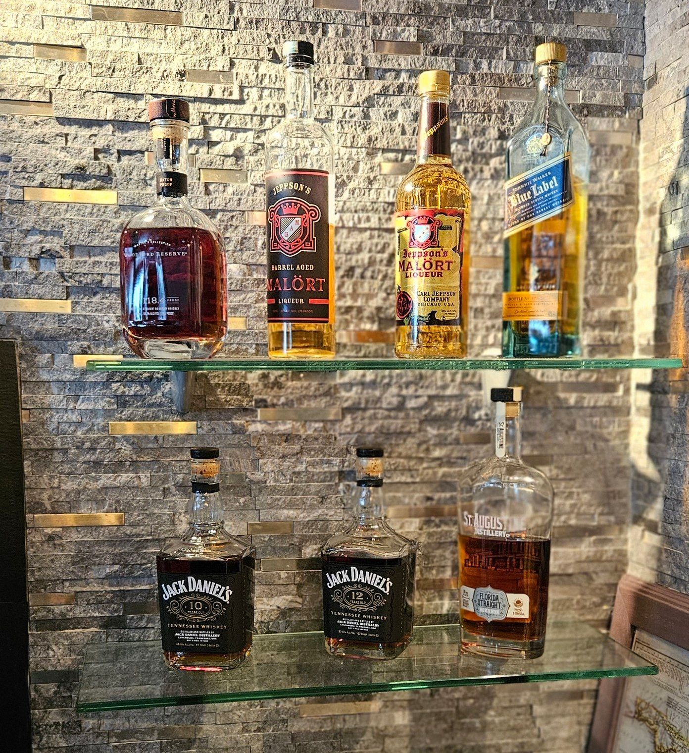 A shelf filled with bottles of alcohol on a brick wall.