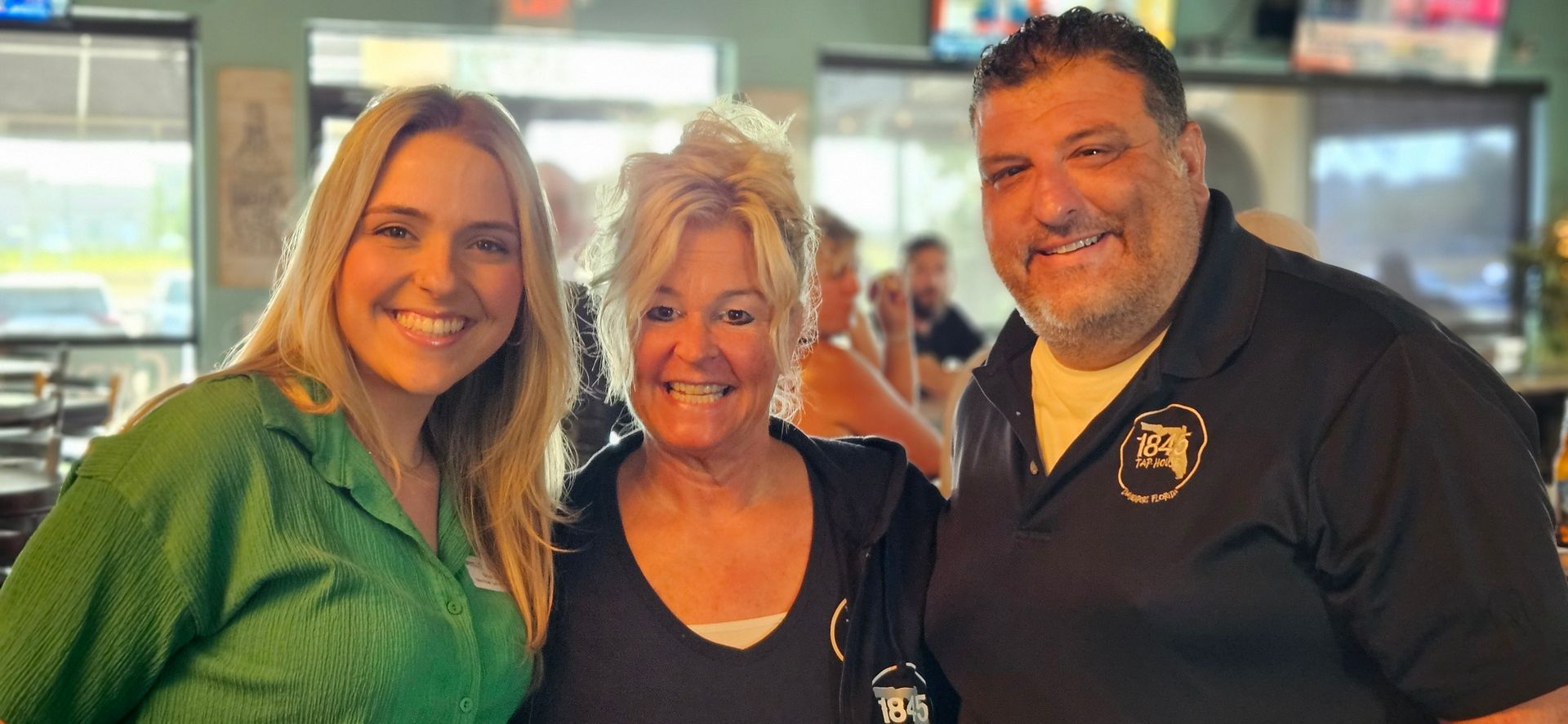 A man and two women are posing for a picture in a restaurant.