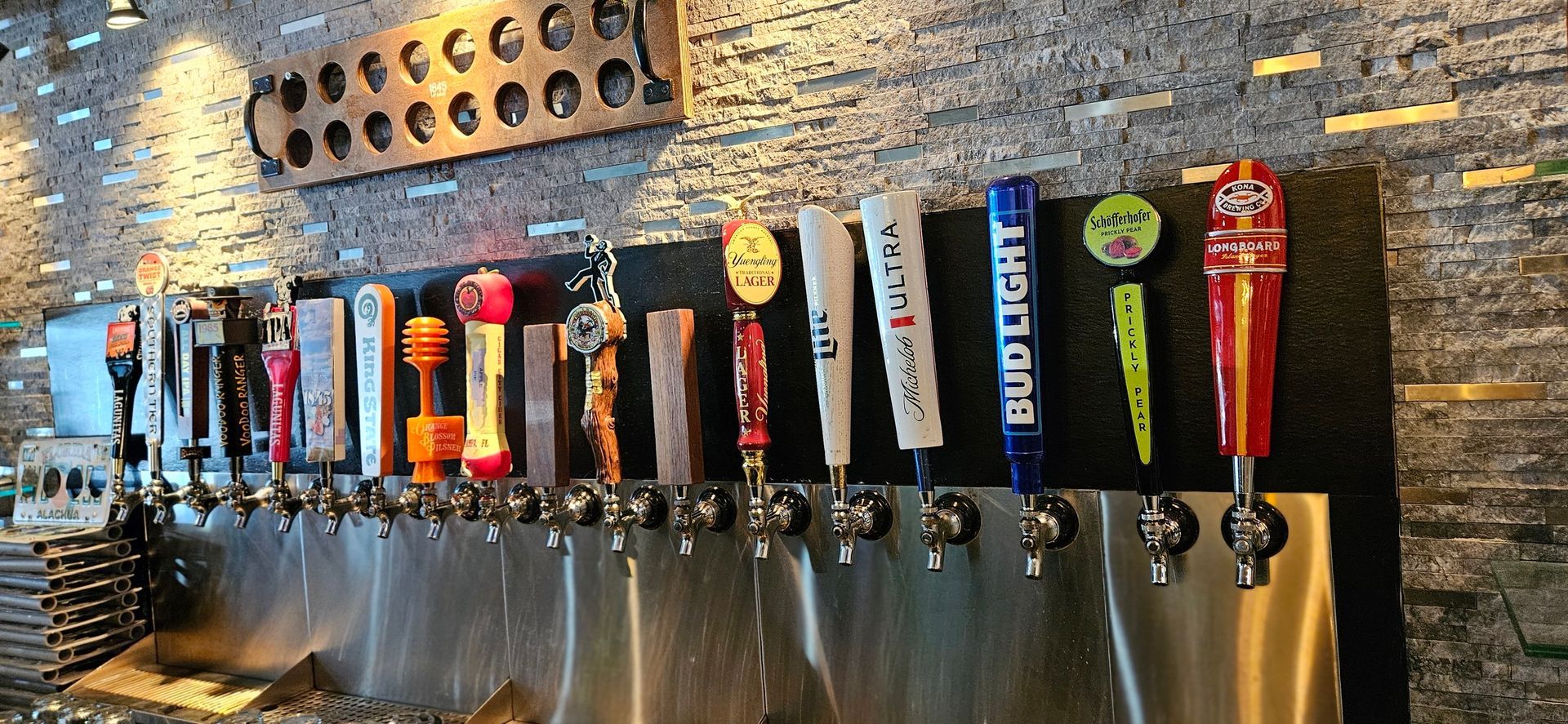 A bunch of beer taps are lined up on a wall.