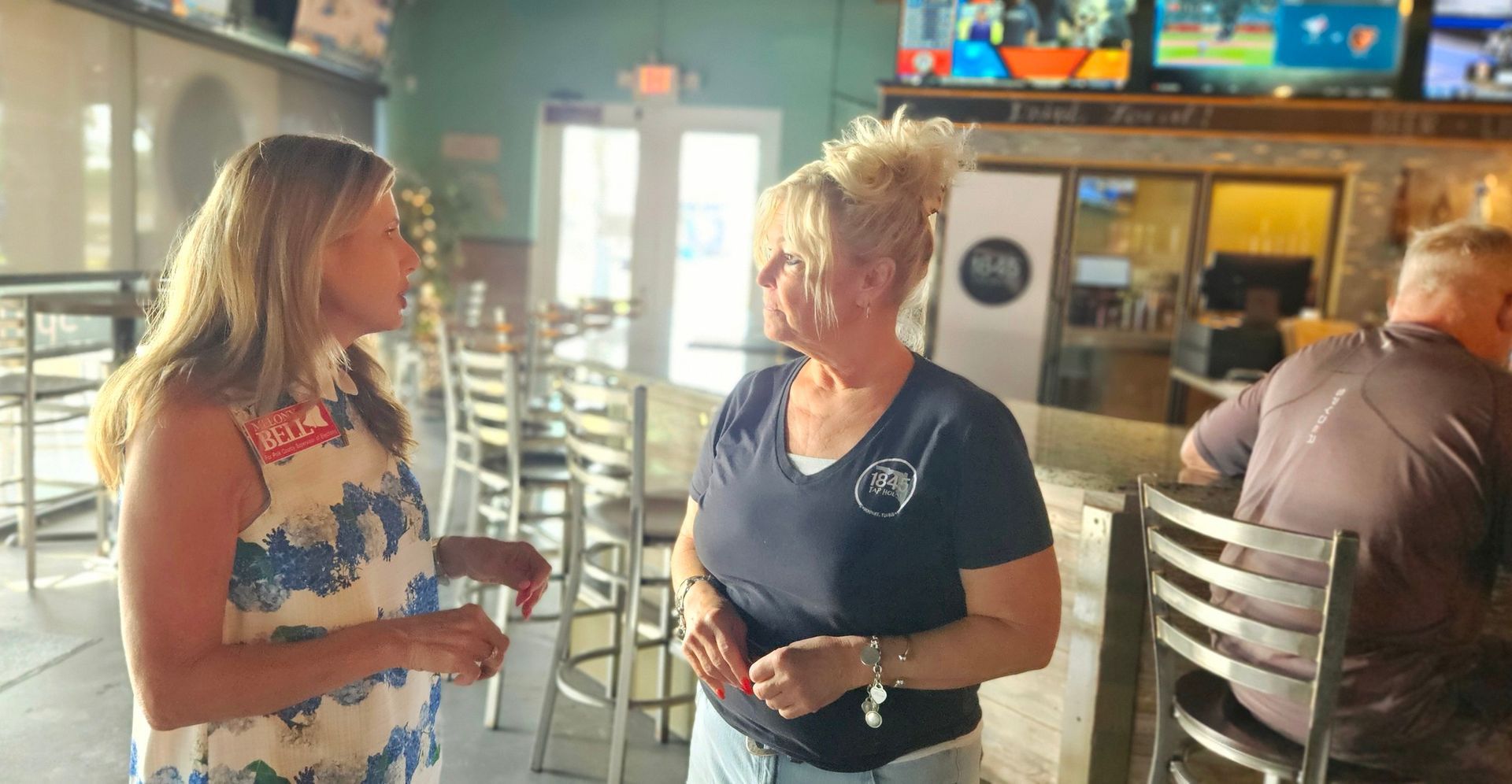 Two women are talking to each other in a restaurant.