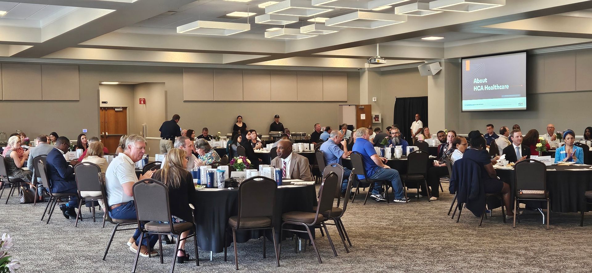 A large room filled with people sitting at tables and chairs.