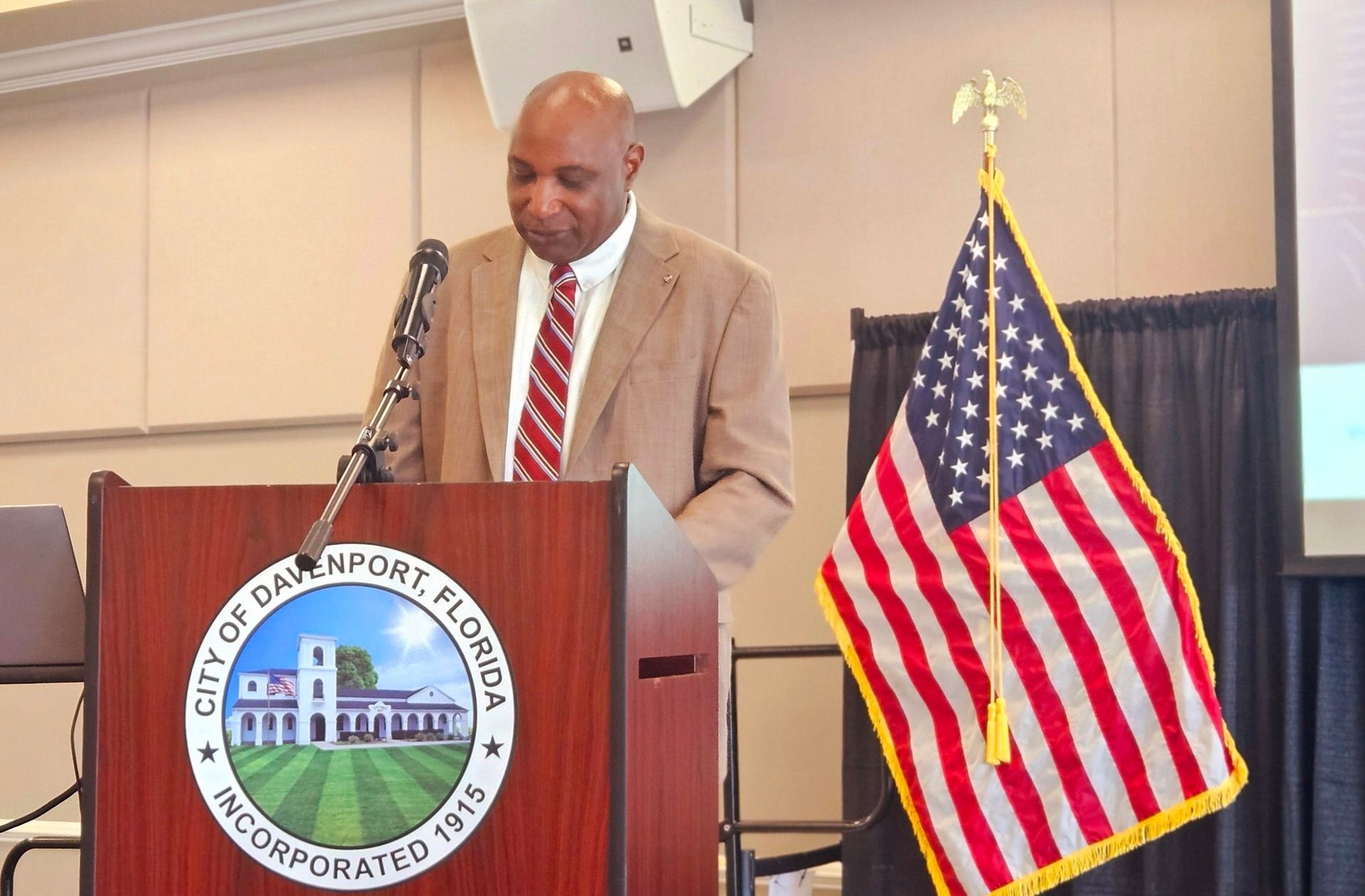 A man stands at a podium in front of an american flag