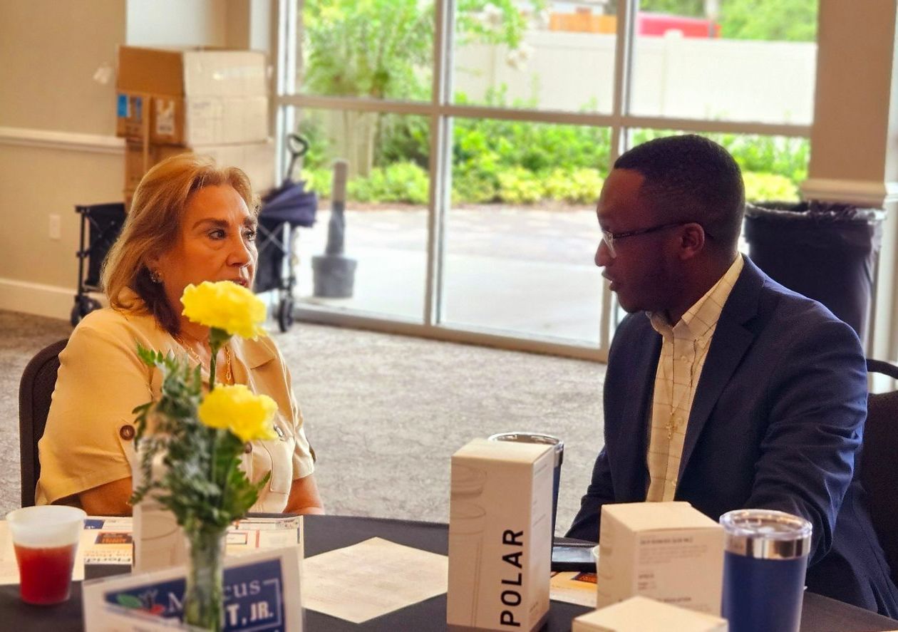 A man and a woman are sitting at a table talking to each other.