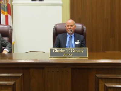 A man in a suit and tie is sitting at a judge 's bench.