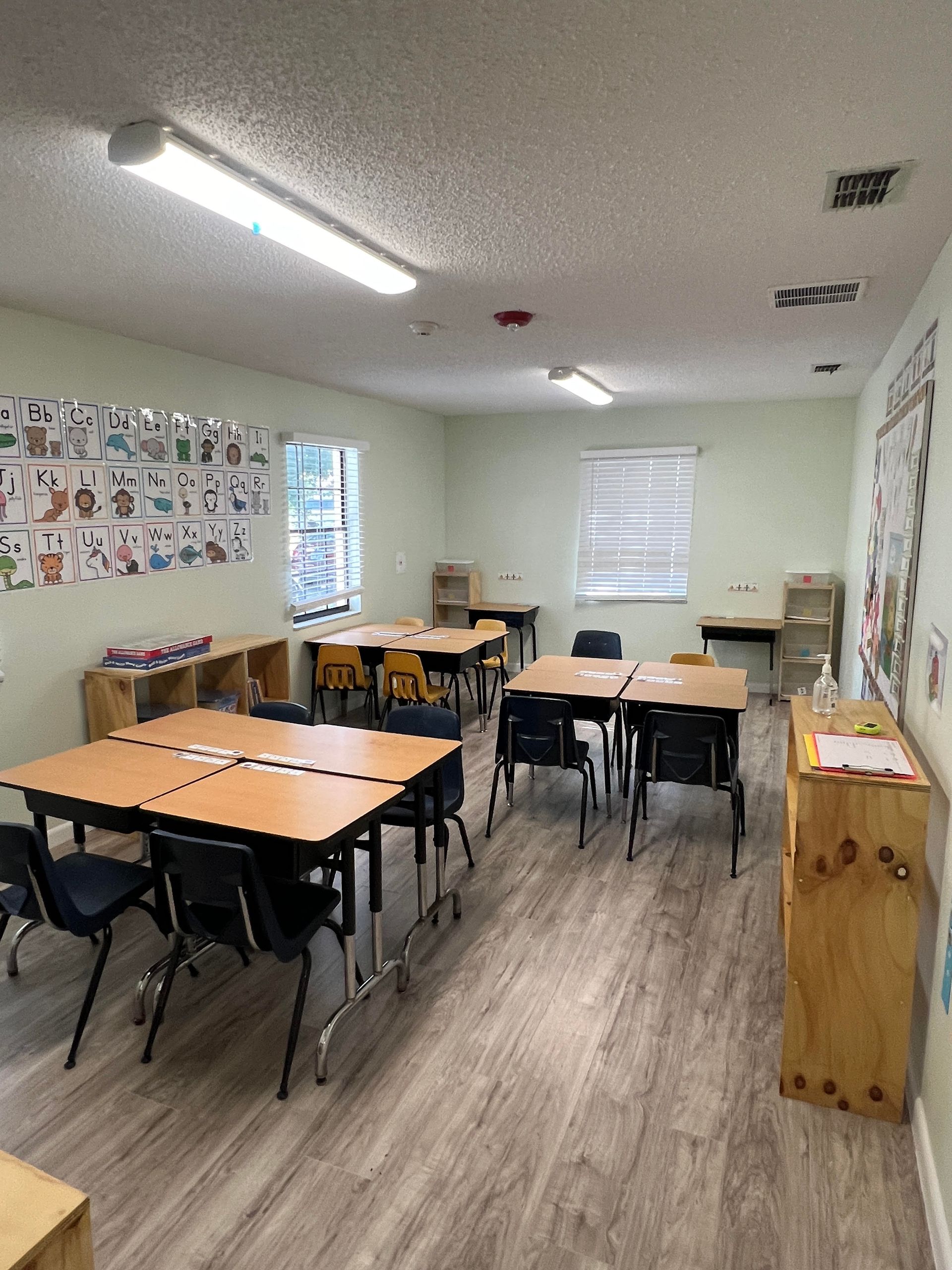 There are many tables and chairs in the classroom.