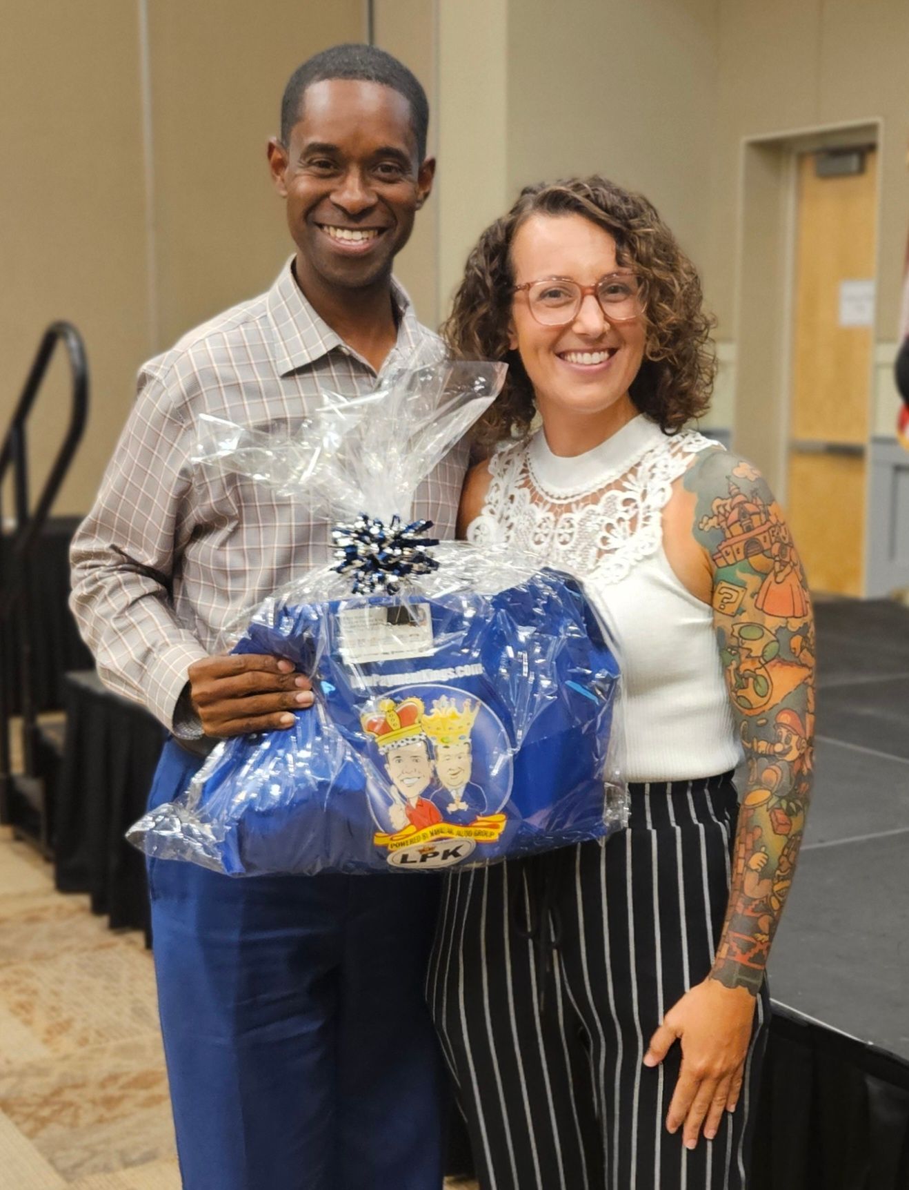 A man and a woman are standing next to each other holding a blue bag.