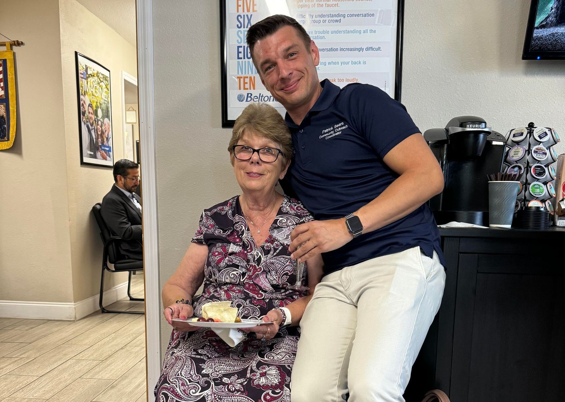 A man is sitting next to an older woman holding a plate of food.