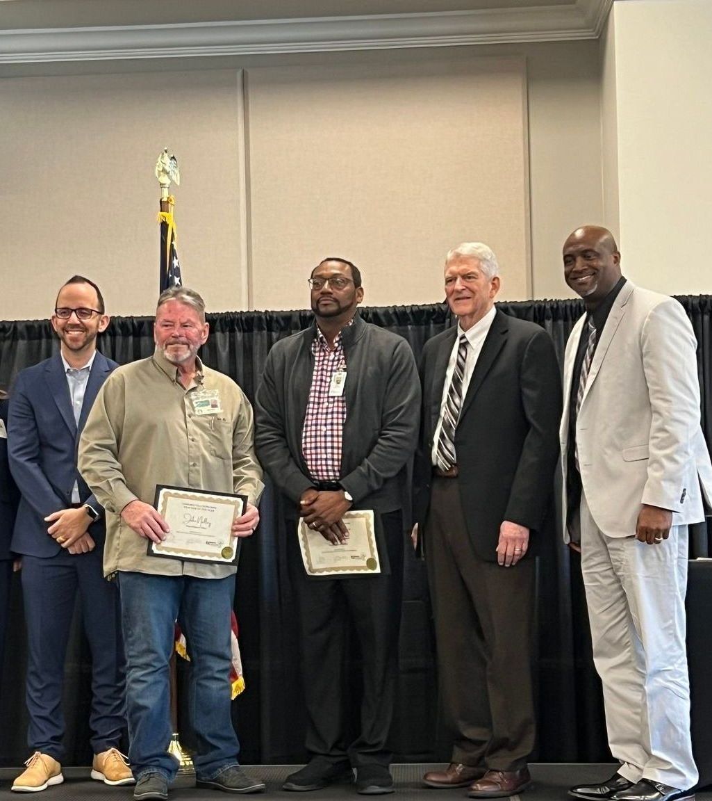 A group of men are posing for a picture and one of them is holding a certificate