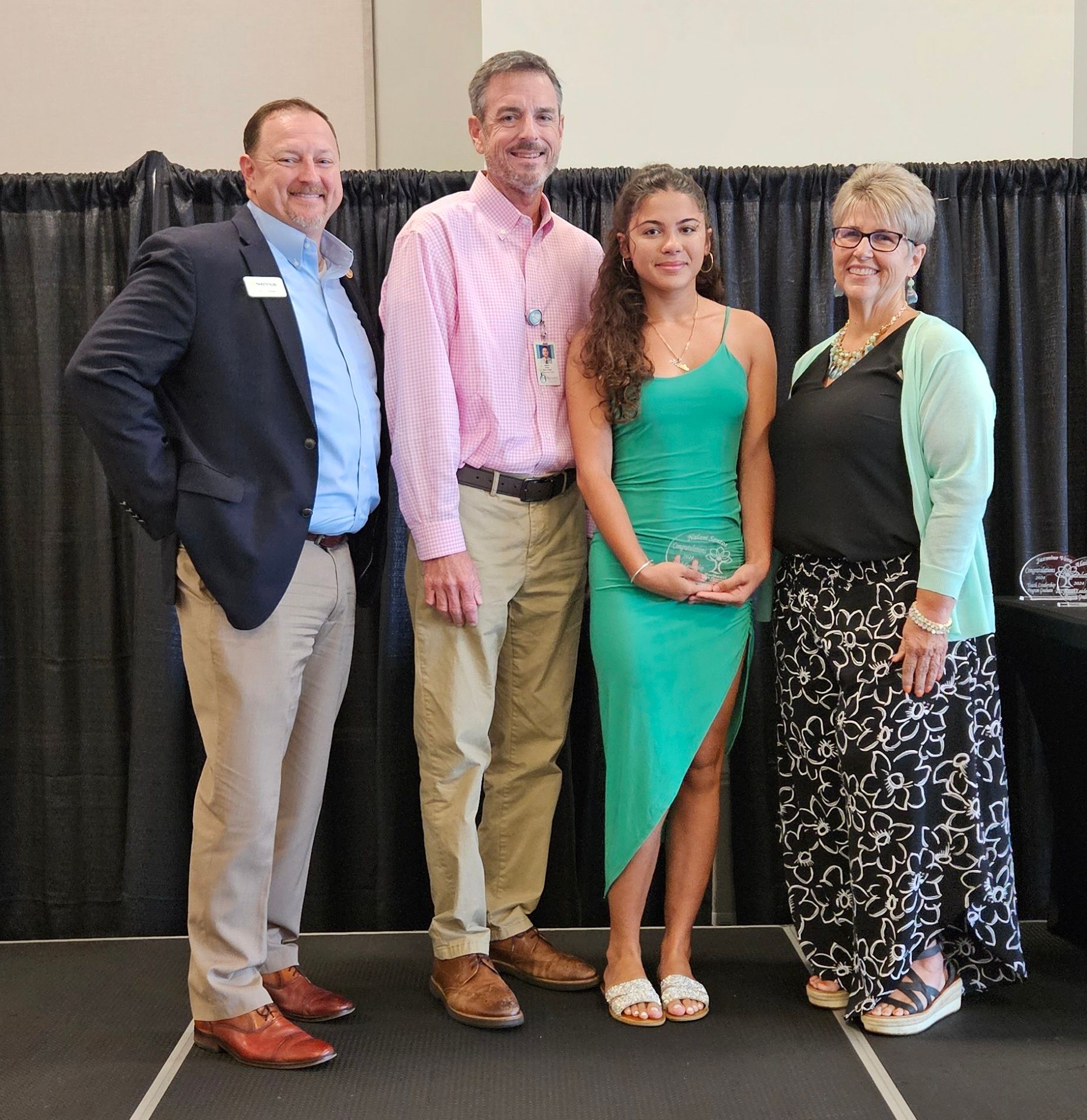 A group of people posing for a picture including a girl in a green dress