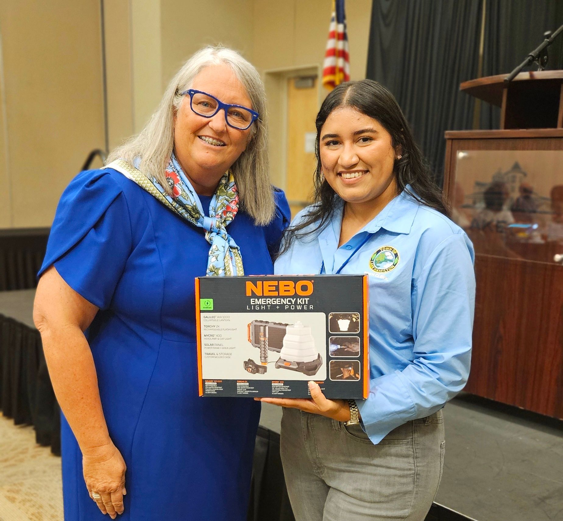 Two women standing next to each other holding a box that says nebo