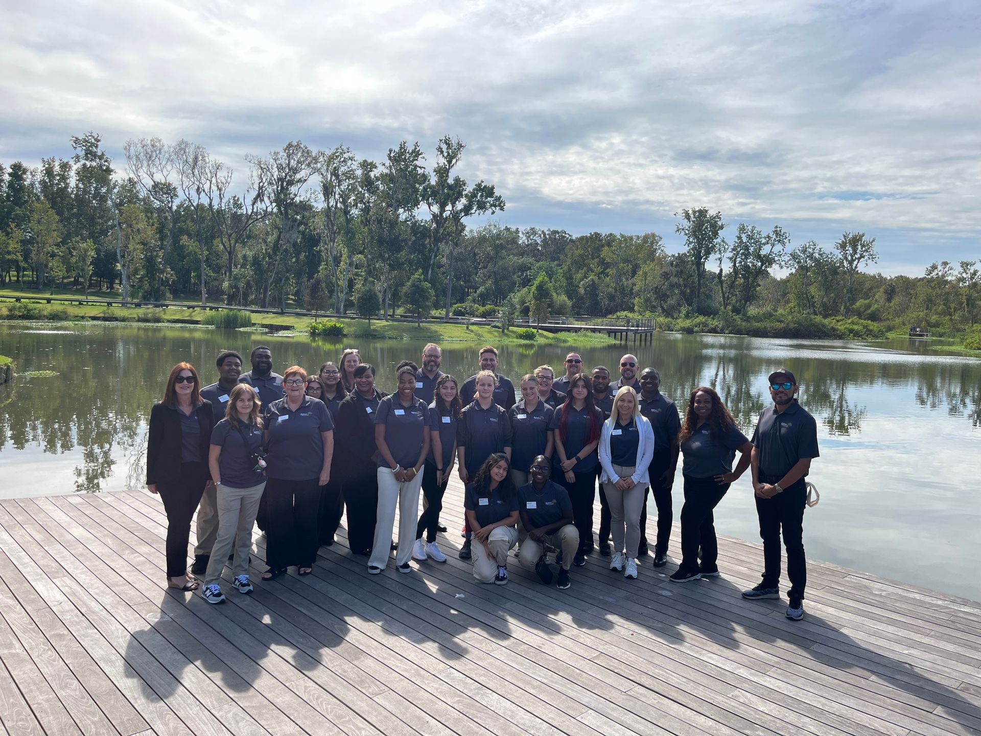 A group of people are posing for a picture on a dock near a lake.