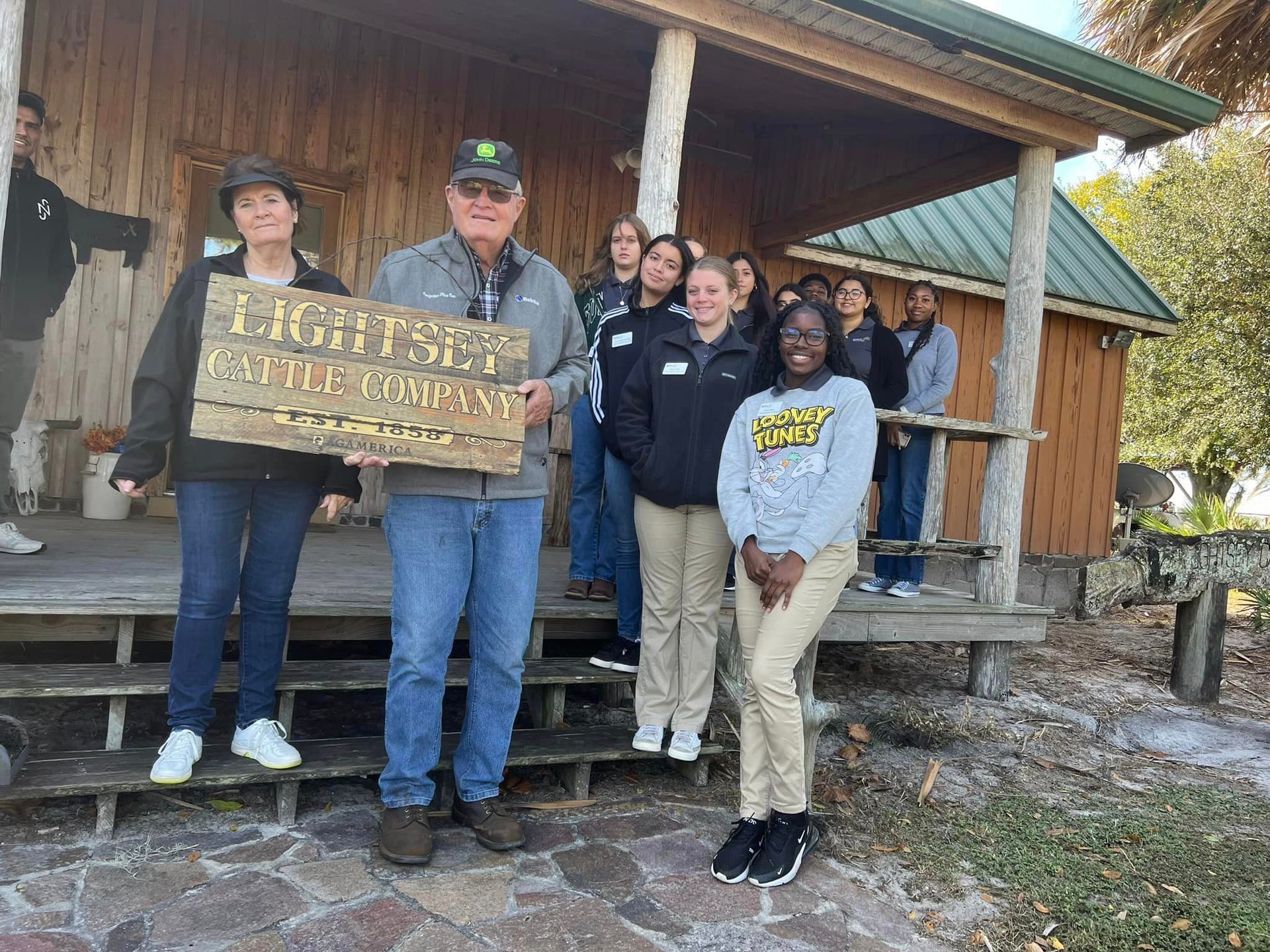 A group of people are standing on a porch holding a sign.