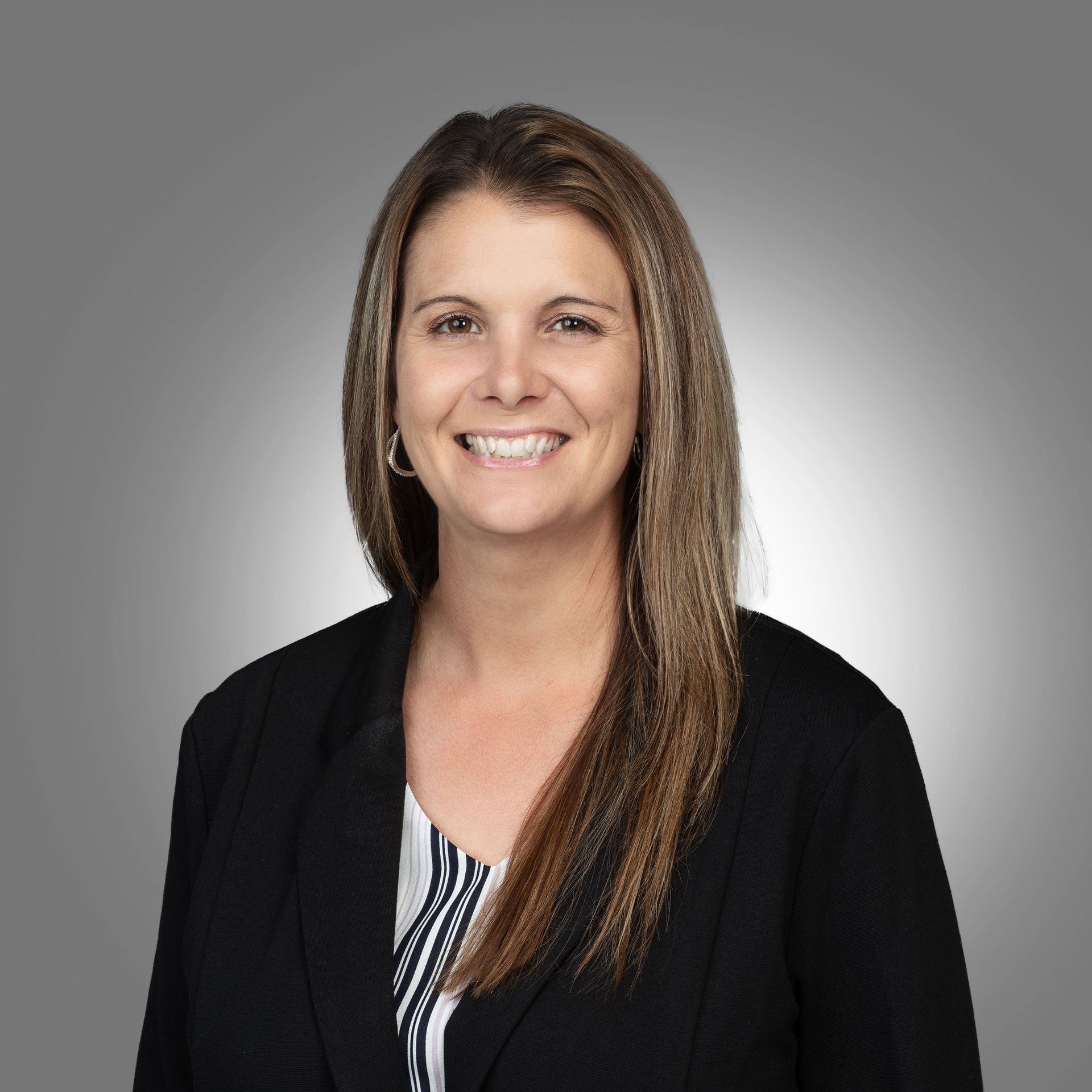 A woman is wearing a black jacket and smiling for the camera.