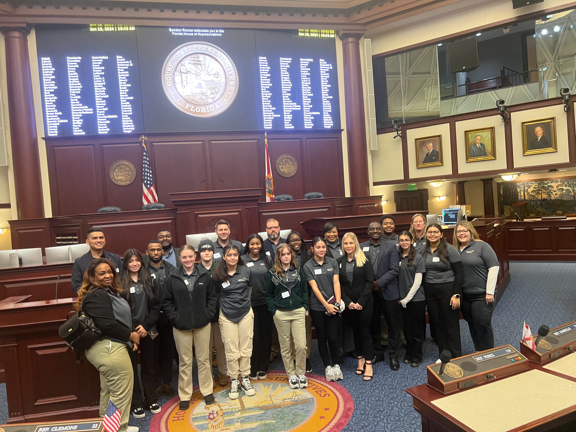 A group of people are posing for a picture in a council chamber.