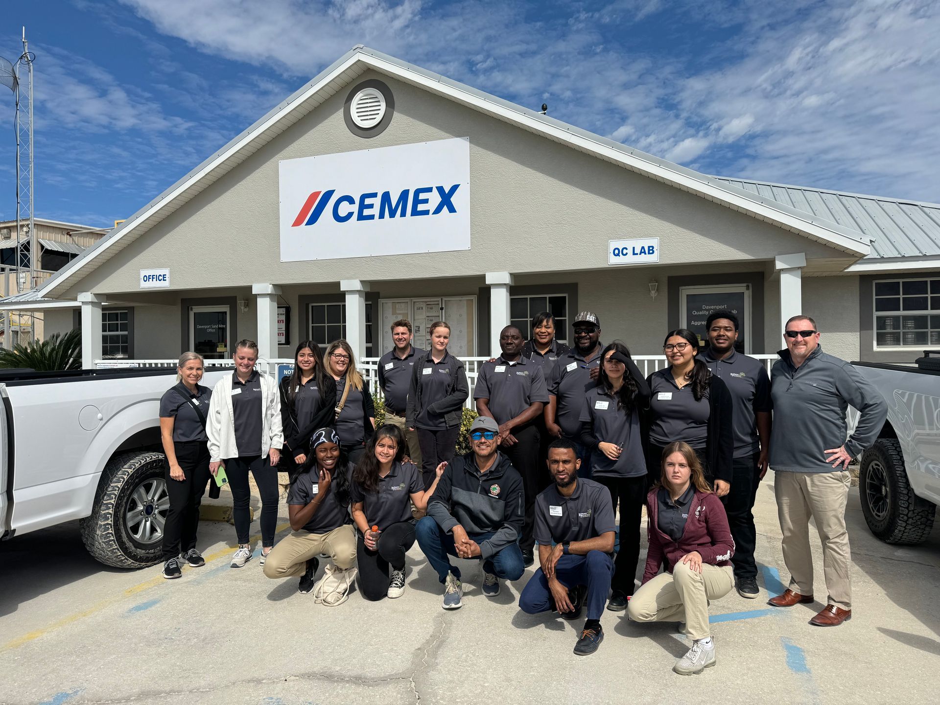 A group of people are posing for a picture in front of a cemex building.