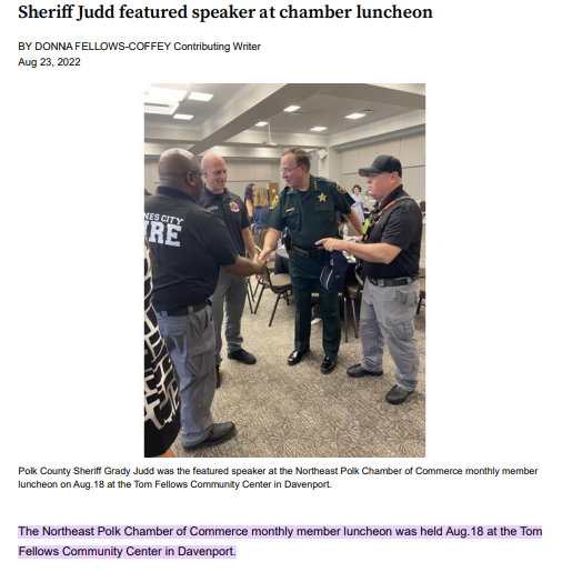 A group of people are cutting a ribbon in front of a building.