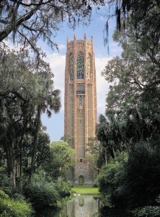 A very tall building is surrounded by trees and water