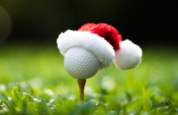 A golf ball is wearing a santa hat on a tee.