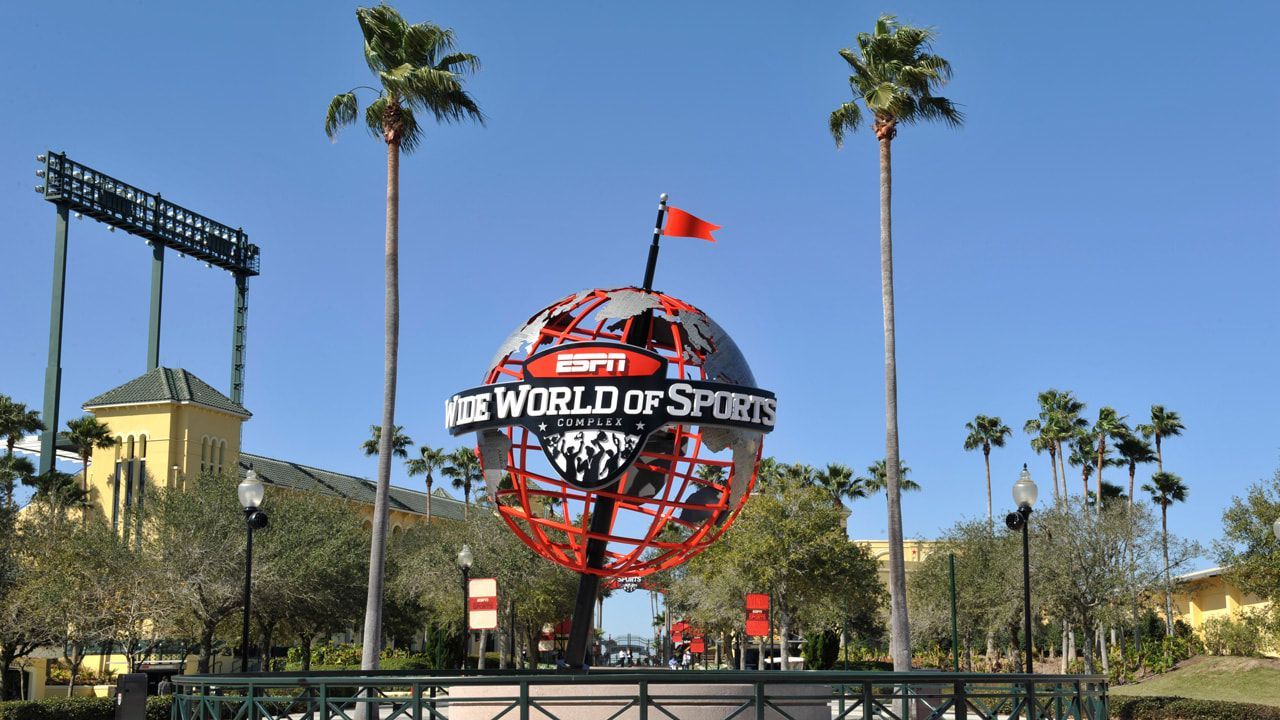 A sign for the world of sports is surrounded by palm trees