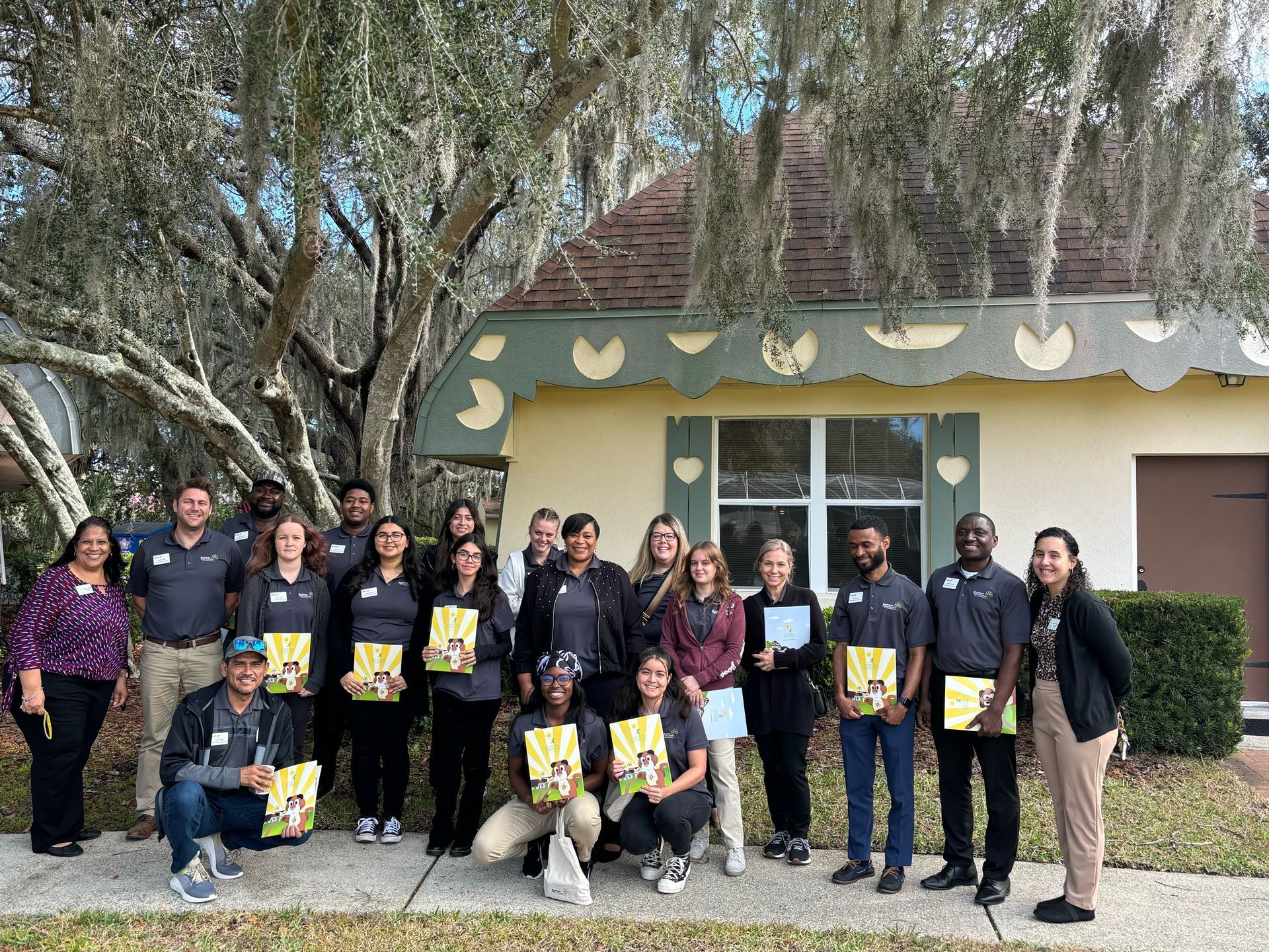 A group of people are posing for a picture in front of a house.