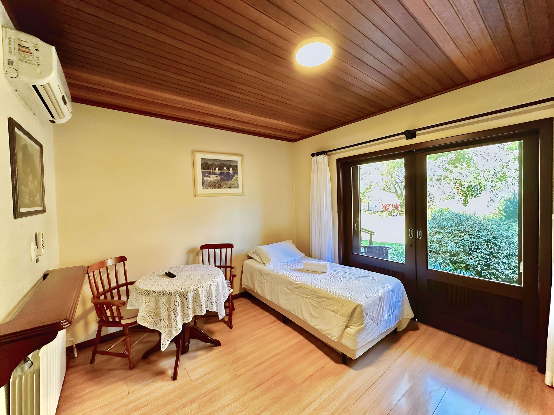 Um quarto com cama de solteiro, mesa e cadeiras.