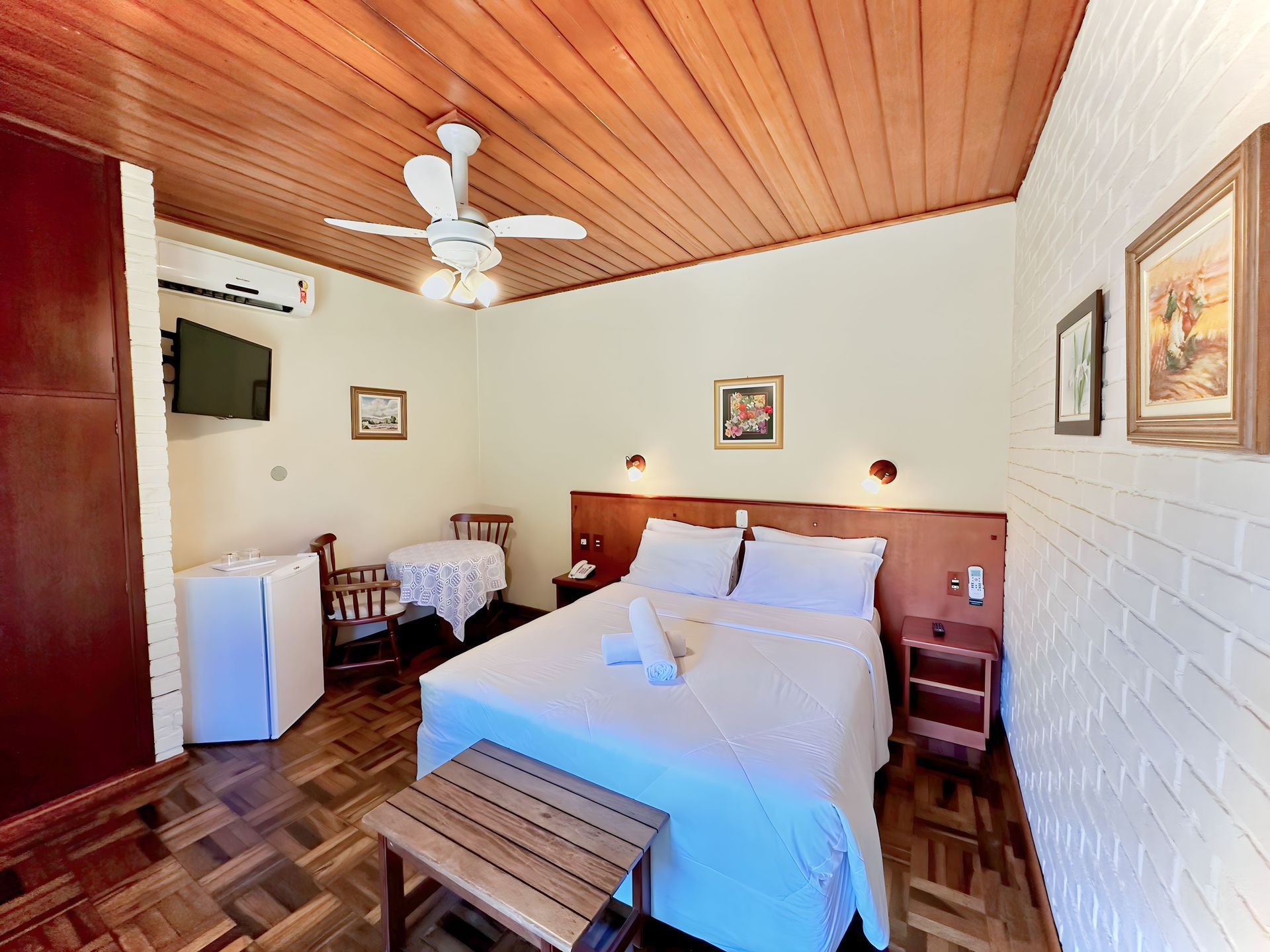 Um quarto de hotel com uma cama grande, ventilador de teto e televisão.