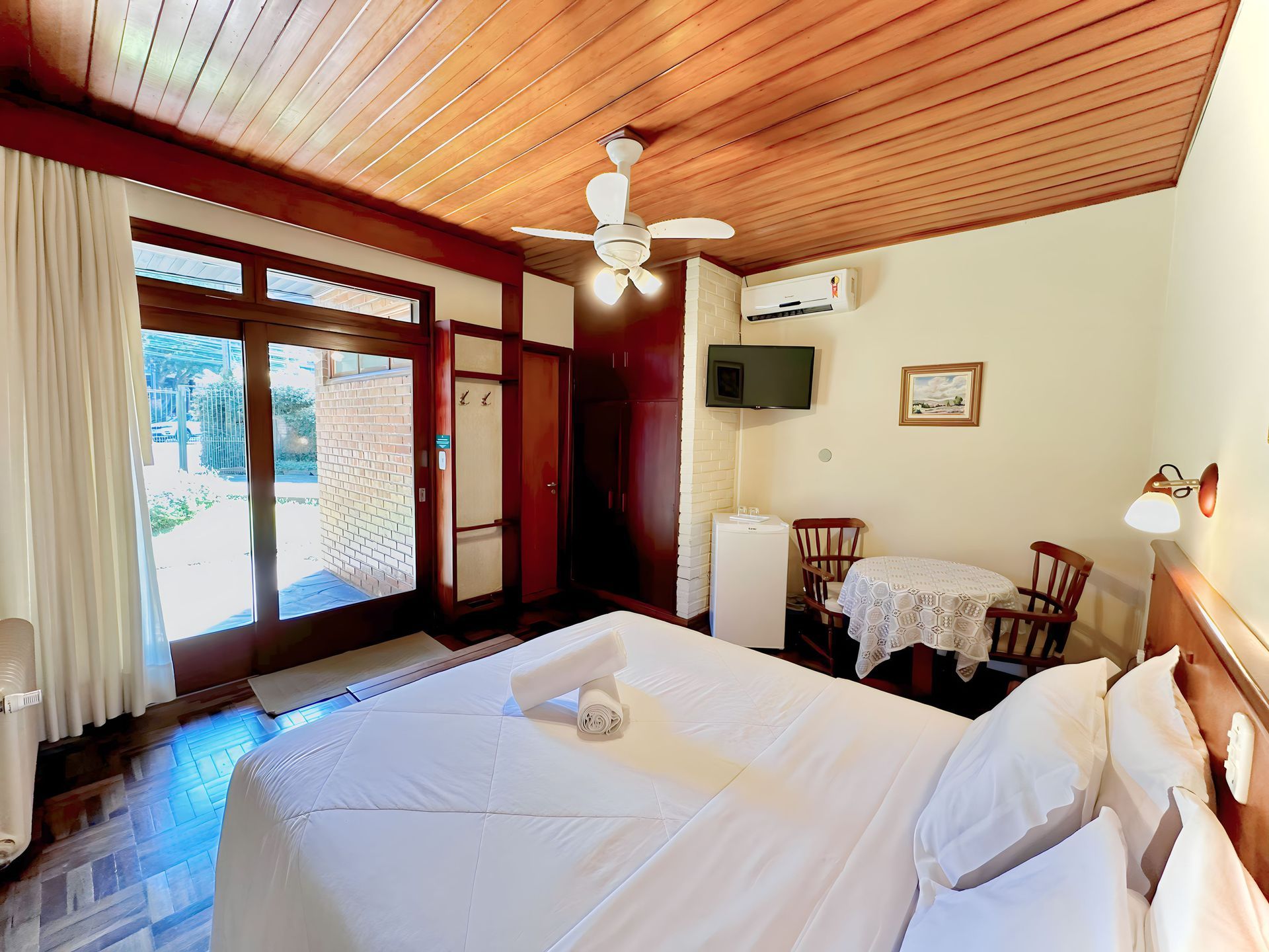 Um quarto com cama, mesa, cadeiras e ventilador de teto.