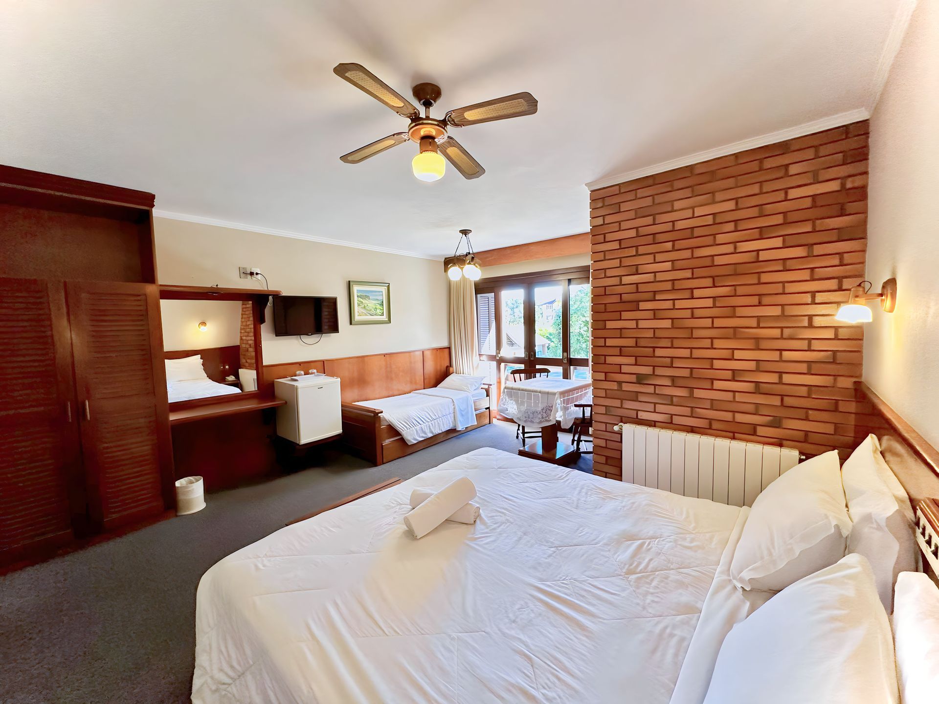 Um quarto de hotel com uma cama grande e ventilador de teto.