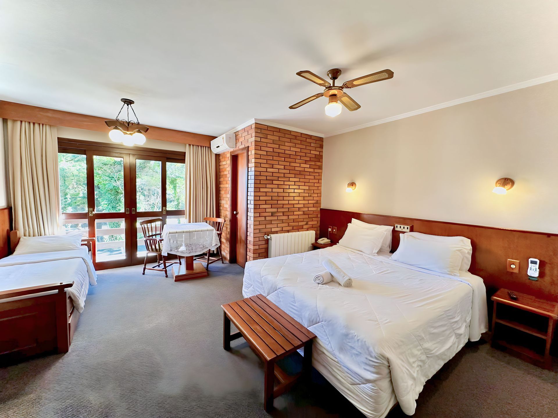 Um quarto de hotel com três camas e ventilador de teto.