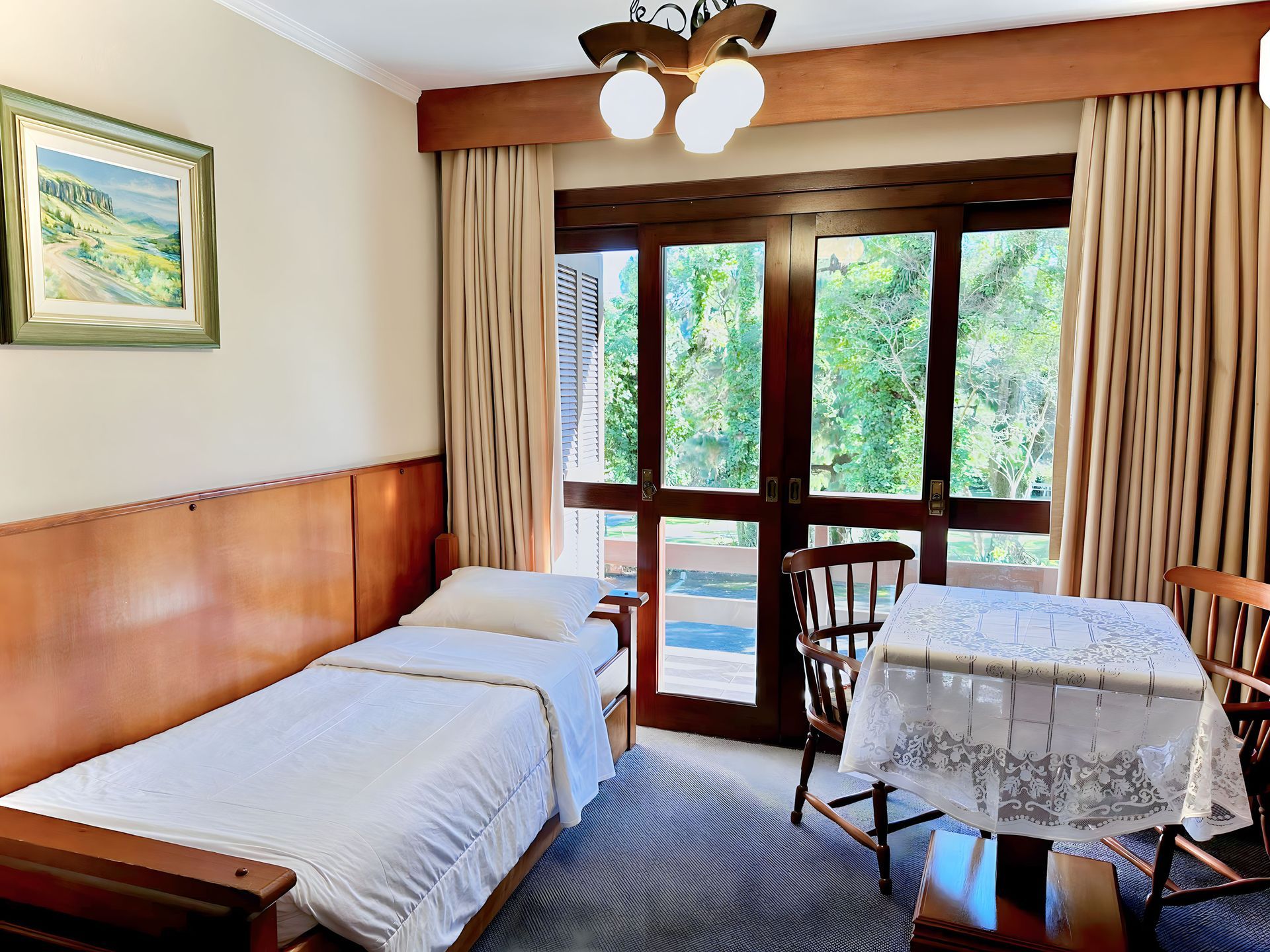 Um quarto com cama de solteiro, mesa e cadeiras.