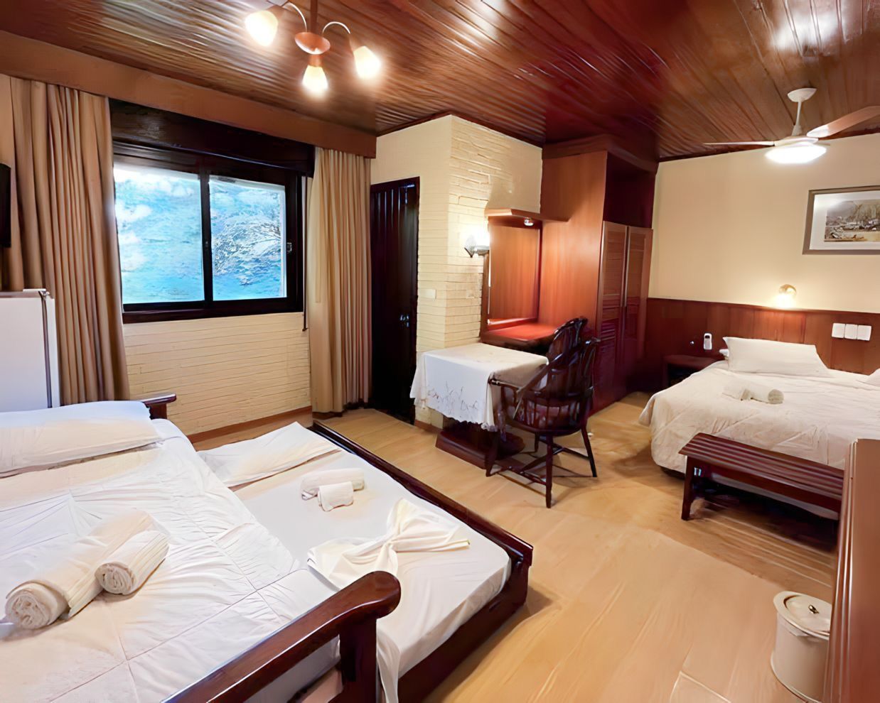 Um quarto de hotel com três camas e ventilador de teto