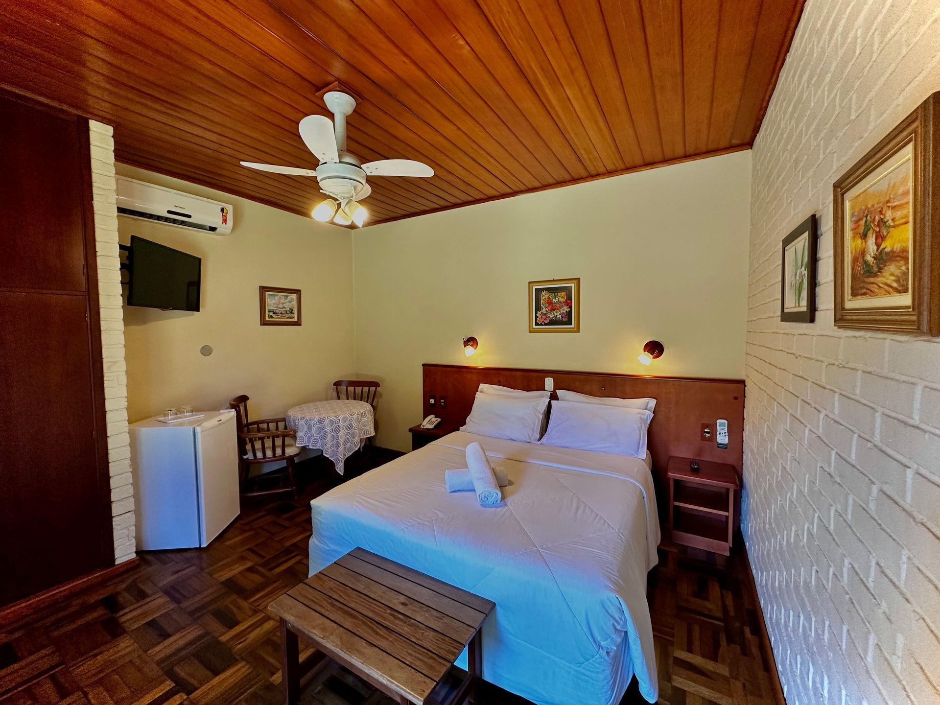 Há um ventilador de teto no quarto com cama.