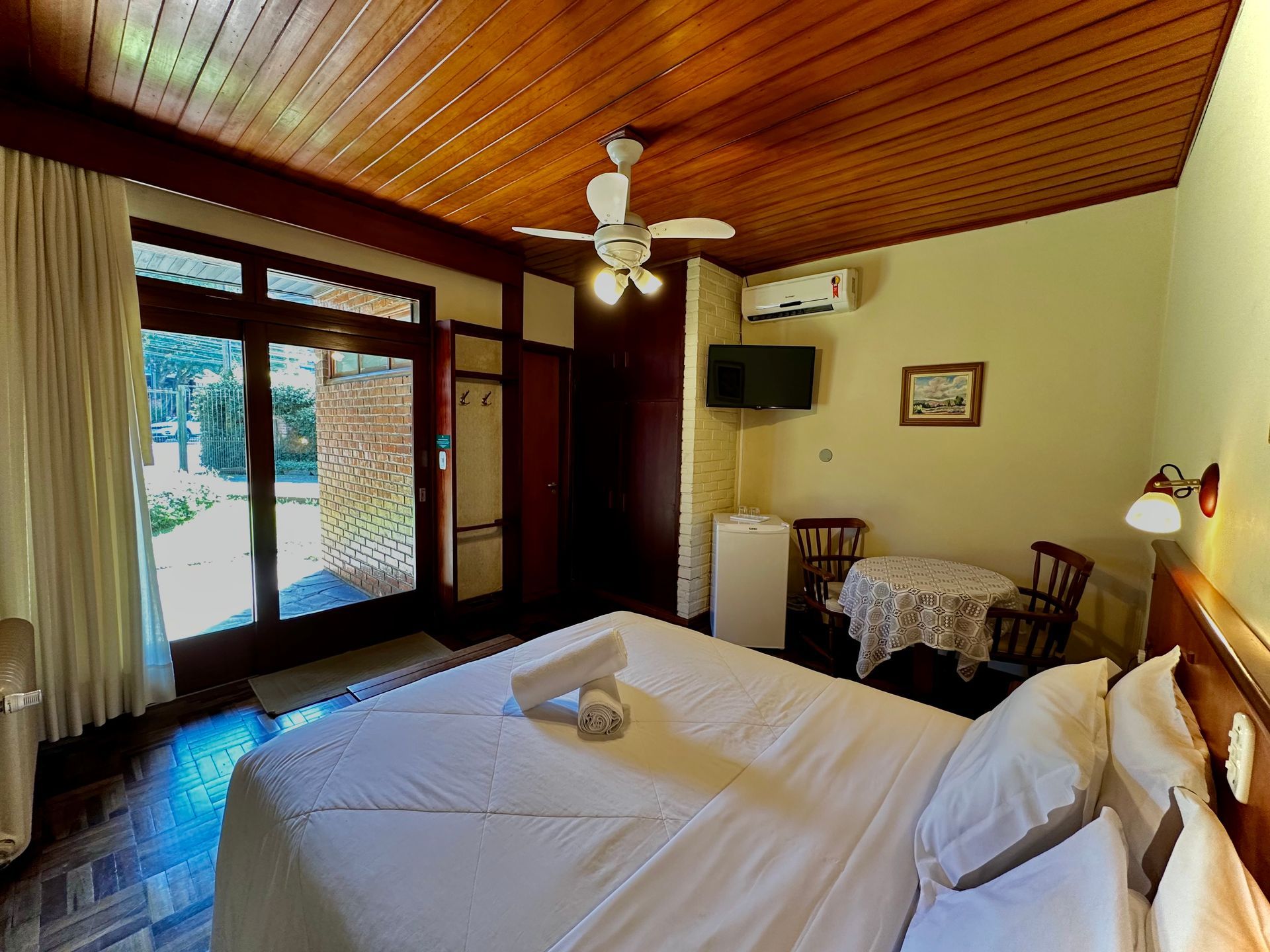 Um quarto com cama, mesa, cadeiras e ventilador de teto.