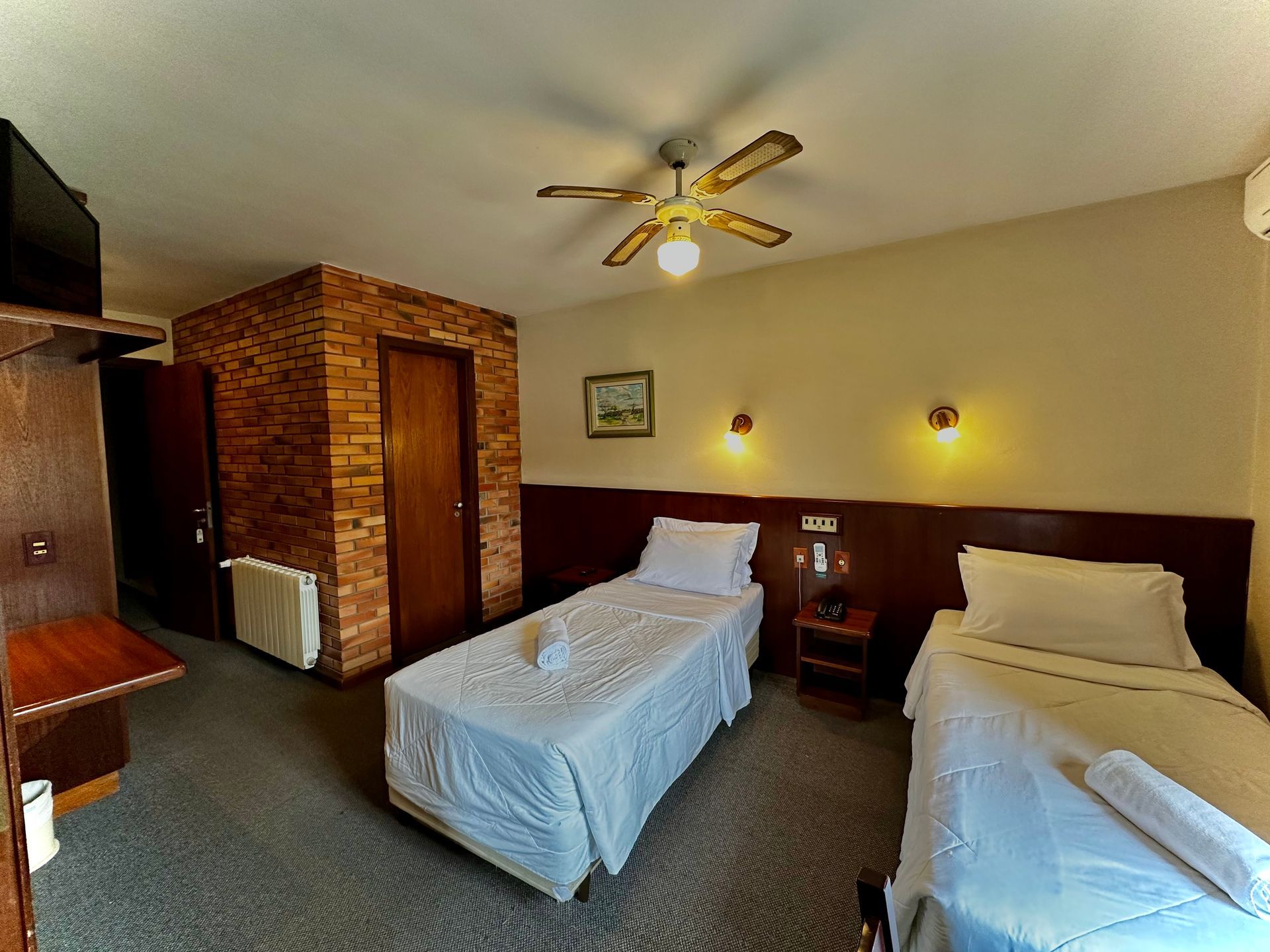 Um quarto de hotel com duas camas e ventilador de teto.