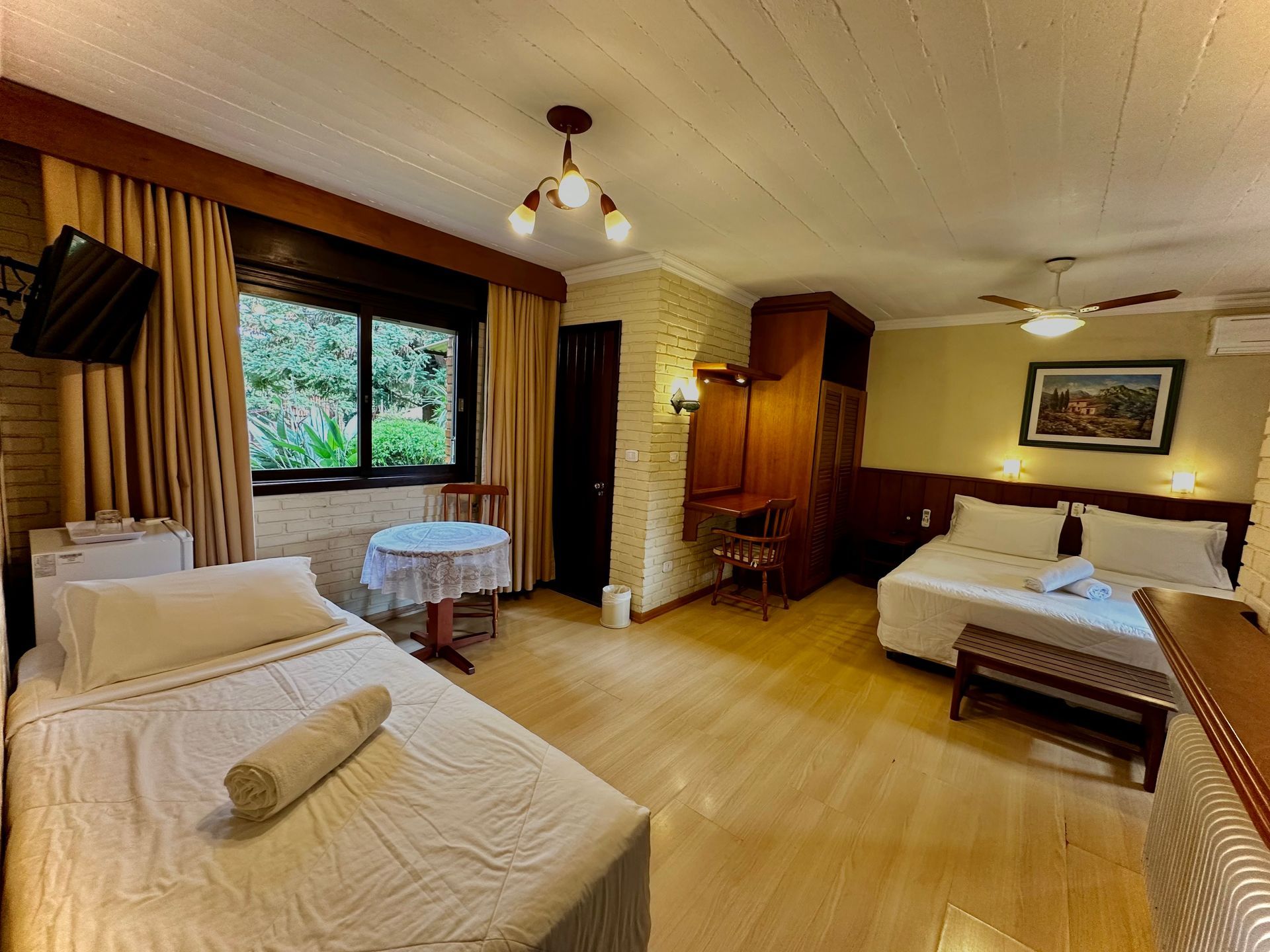 Um quarto de hotel com duas camas, uma mesa e uma televisão.