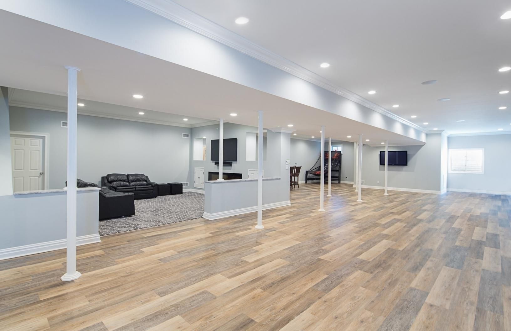 A large empty basement with hardwood floors and a couch.